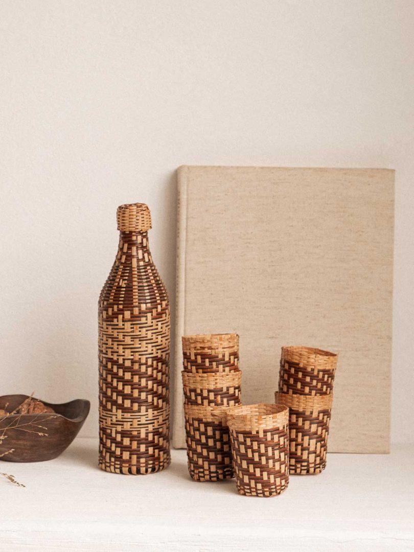 ensemble composé d'une bouteille de verre recouverte de rotin tressé et de 6 cache verre en rotin tressé.