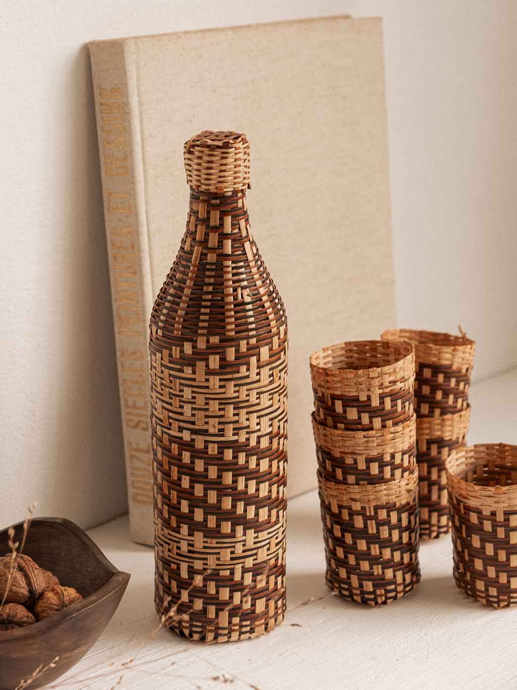 ensemble composé d'une bouteille de verre recouverte de rotin tressé et de 6 cache verre en rotin tressé.