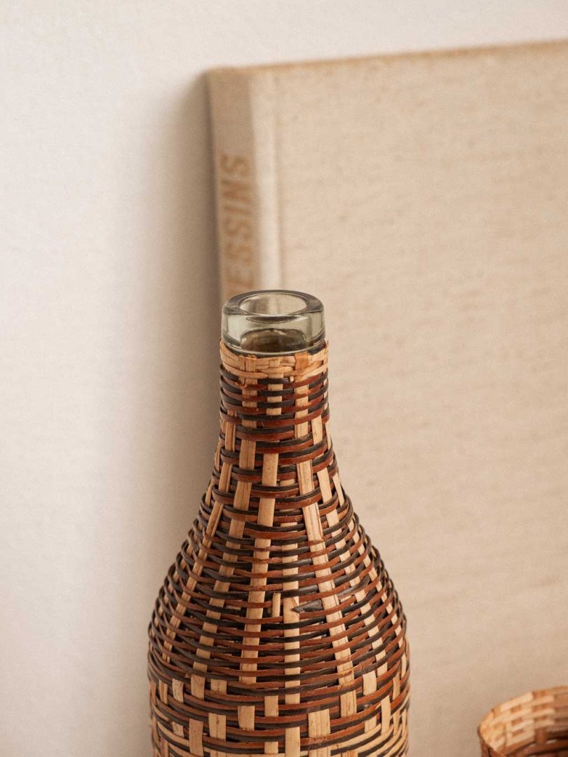 ensemble composé d'une bouteille de verre recouverte de rotin tressé et de 6 cache verre en rotin tressé.